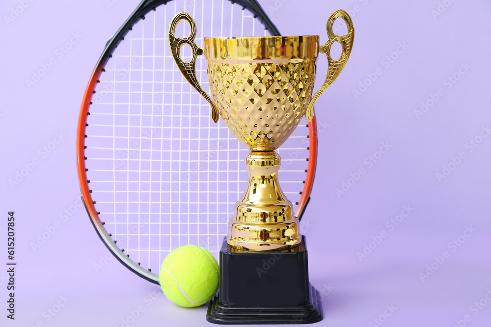 Gold cup with tennis racket and ball on lilac background Stock Photo
