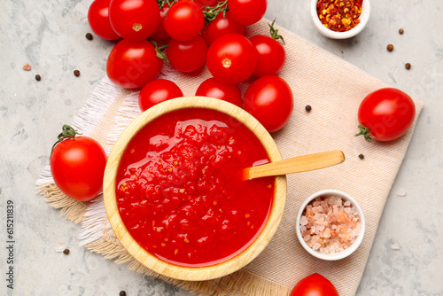 Bowl with tasty tomato sauce and fresh vegetables on grunge background