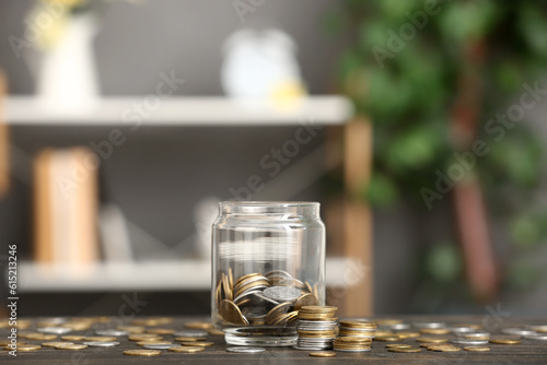 Jar with coins on table against blurred background. Savings concept