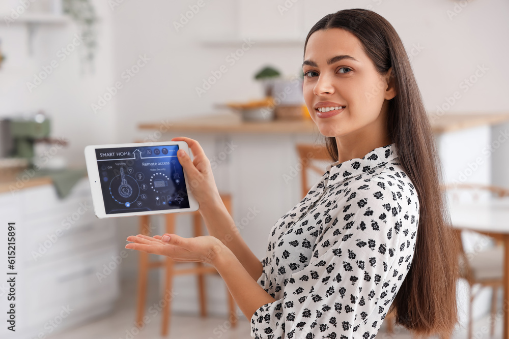 Young woman with smart home security system control panel in kitchen, closeup Young woman with smart home security system control panel in kitchen, closeup