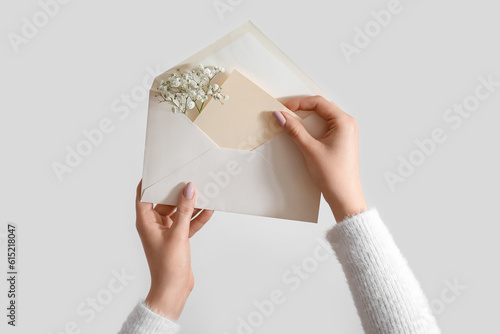 Woman holding envelope with blank invitation card and gypsophila flowers on white background