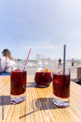Two glasses of sangria and a pitcher on the table of a bar terrace with the blue sky background for copy space
