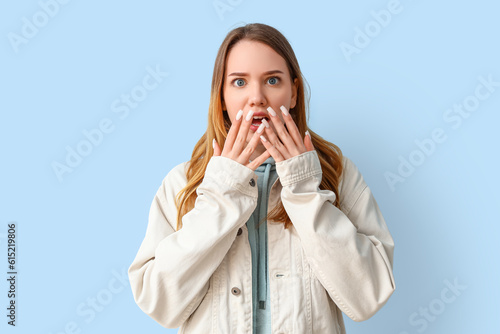 Shocked young woman on blue...