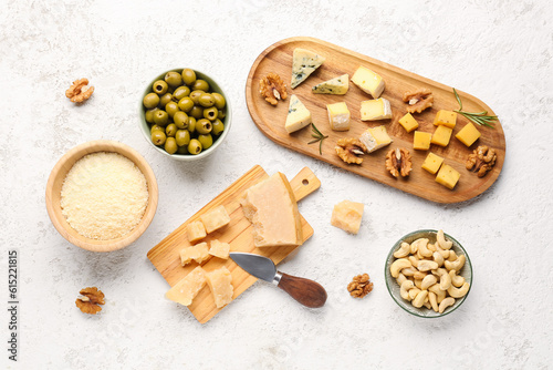 Wooden boards with pieces of tasty cheese, grated Parmesan and nuts on light background