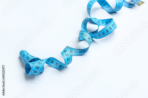 Blue measuring tape on light background, closeup