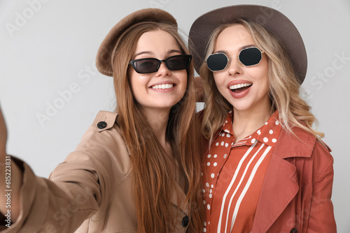 Young sisters taking selfie on light background, closeup