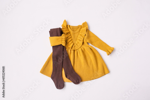 Yellow dress and brown leggings. Look for a girl. Children's wardrobe. Layout, white background, top view