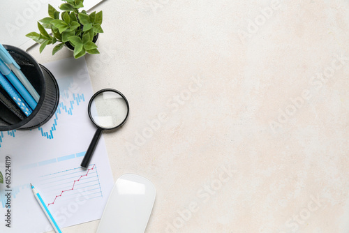 Magnifier with business charts on white table in office photo