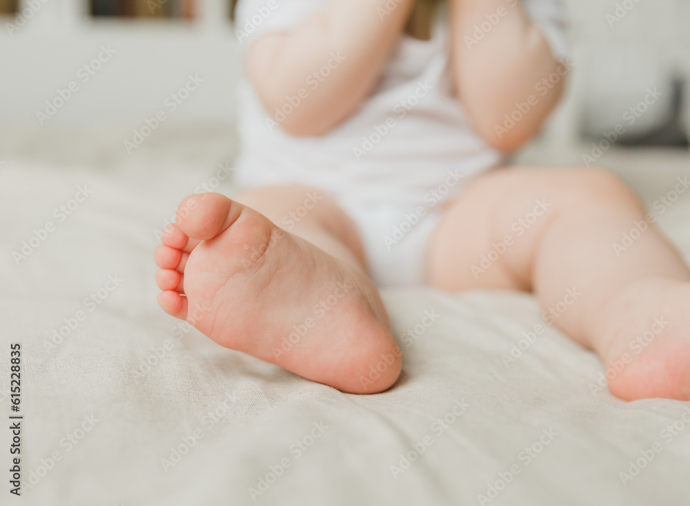 mom's hands hold the baby's legs in on a cotton bed, hygiene and care and care for the newborn.toddler's heel