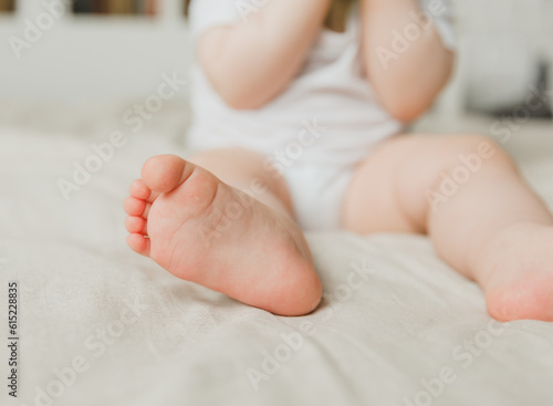 mom's hands hold the baby's legs in on a cotton bed, hygiene and care and care for the newborn.toddler's heel
