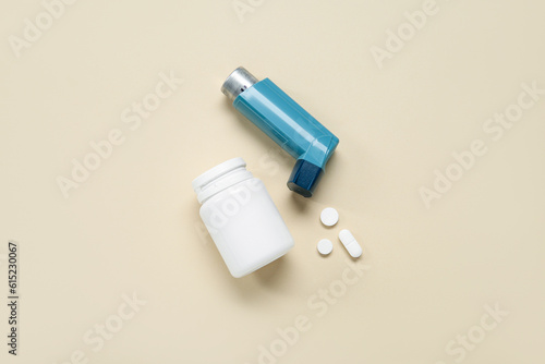 Asthma inhaler and box with pills on beige background