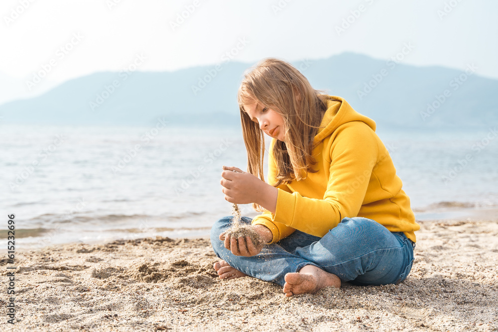 Lonely beautiful sad girl teenager sits thoughtfully on sand sea beach. Dreams,anxiety,worries about future,school friends, parents. Teen bullying, psychological problems in adolescent puberty period