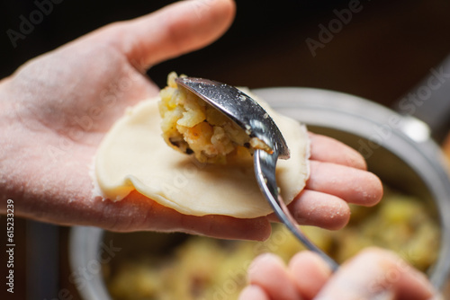 Sculpting dumplings close-up. Women's hands make dumplings stuffed with potatoes and mushrooms.