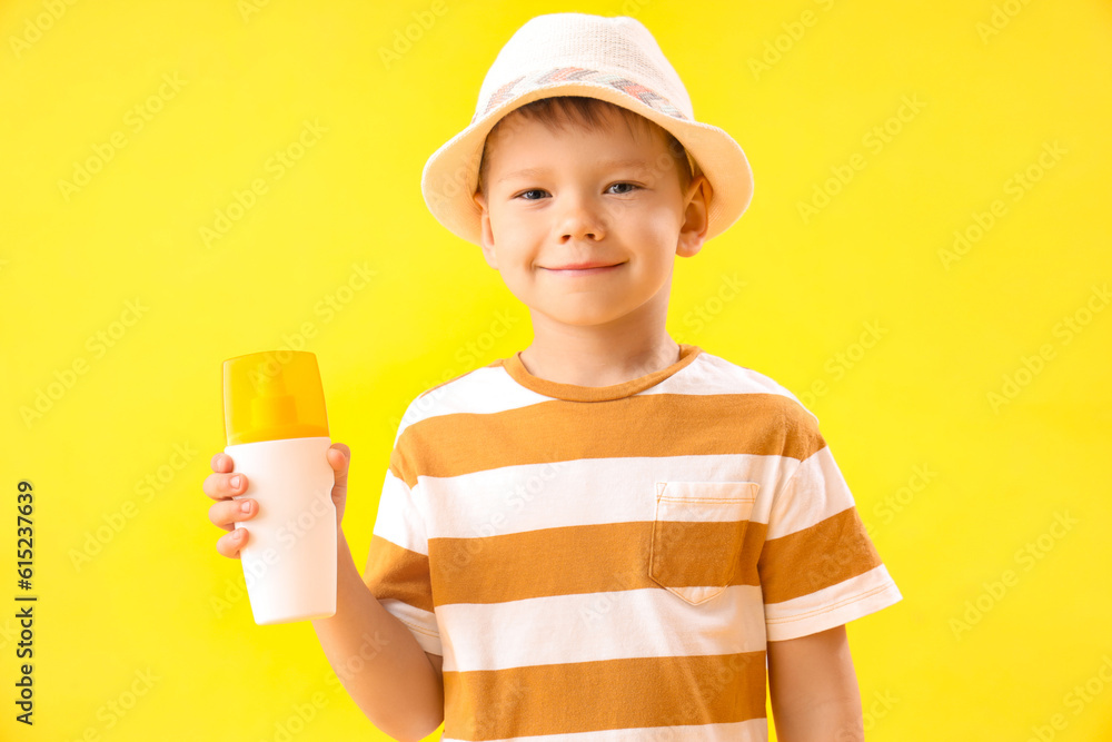 Little boy with bottle of sunscreen cream on yellow background Little boy with bottle of sunscreen cream on yellow background