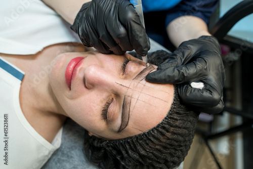 Makeup artist plucks eyebrows in a beauty salon.