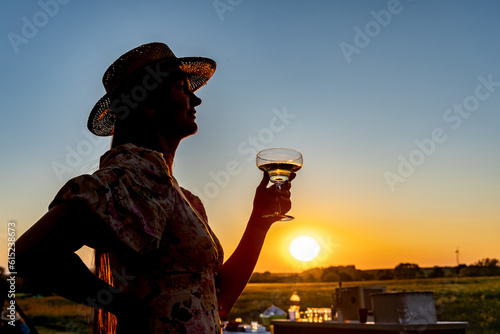 A woman with a glass of wine on a sunset background