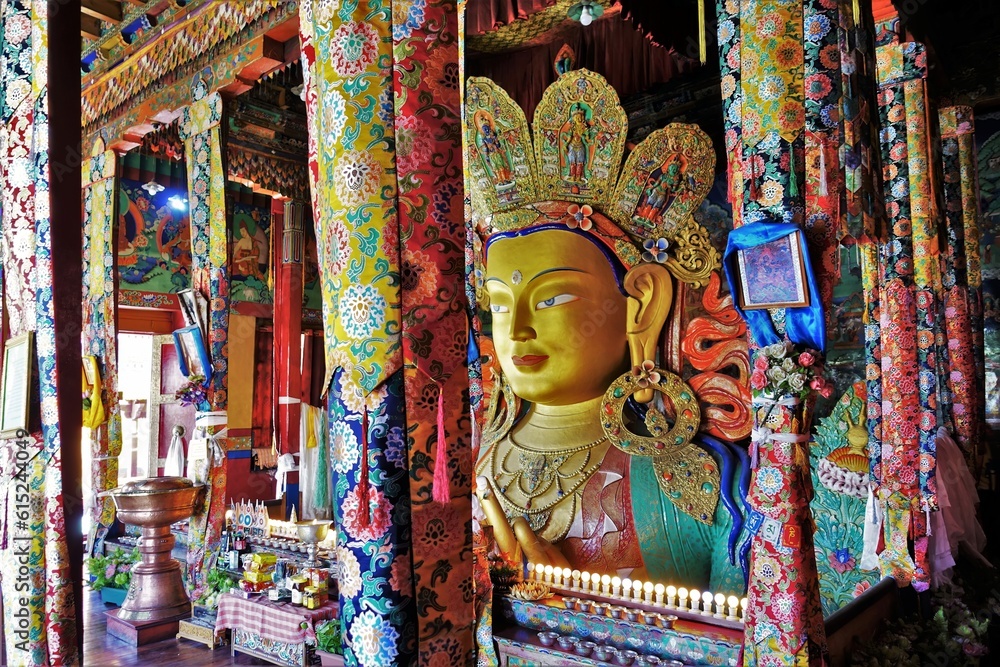 Discover the grandeur of Thiksey monastery in Indian Ladakh, featuring a colossal two-story high Buddha statue adorned with vibrant decorations, exuding tranquility and cultural richness.