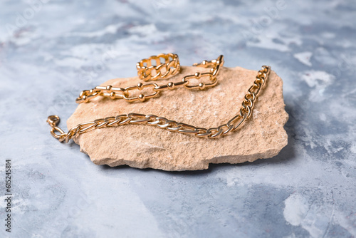 Stone with beautiful ring and chain bracelets on blue background