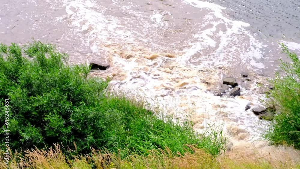 dirty muddy water flows, pouring from sewer pipe into the river, waste