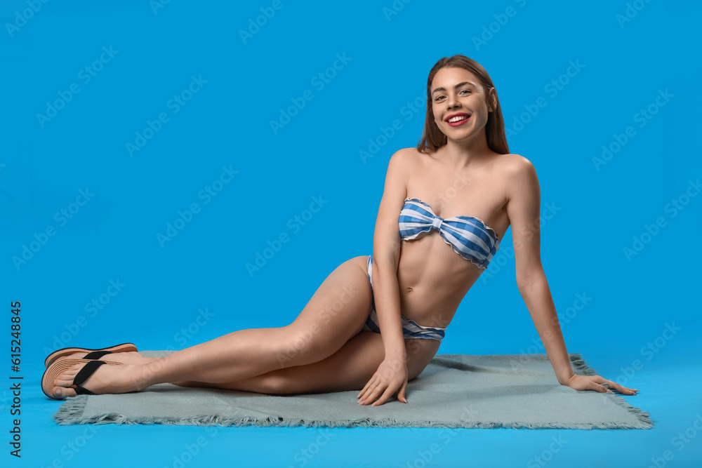 Obraz premium Young woman in swimsuit sitting on blue background
