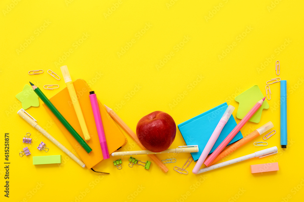 Naklejka premium Fresh red apple with different stationery on yellow background