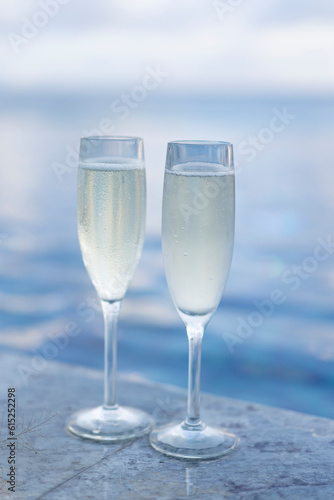 Two glasses of champagne on the side of the infinity pool against the backdrop of a sunset in the Maldives