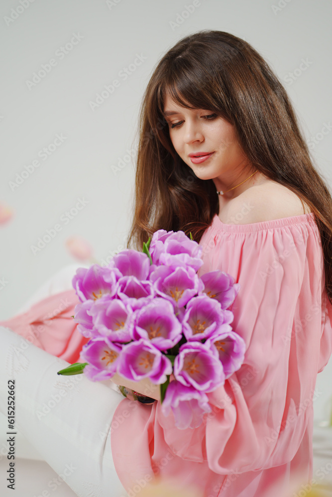 beautiful young brunette woman with long hair in pink with a bouquet of tulips. beautiful young brunette woman with long hair in pink with a bouquet of tulips.