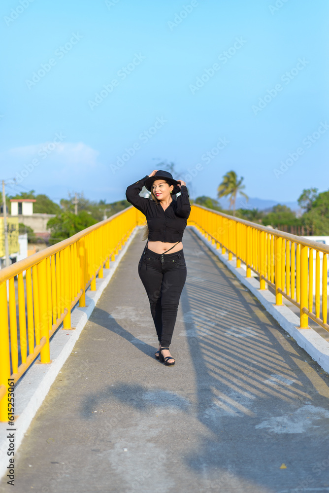 Portrait of young woman with positive attitude on a pedestrian bridge. Sunset with blue sky.