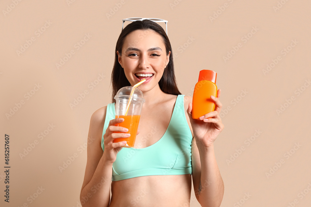 Young woman with sunscreen cream and cup of juice on beige background Young woman with sunscreen cream and cup of juice on beige background