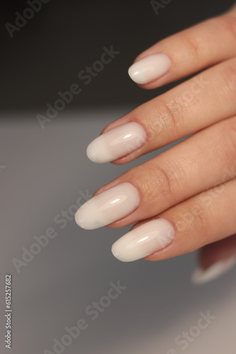 Nude manicure. Long almond shaped nails. Nail design. Manicure with gel polish. Close-up of the hands of a young woman with a gentle nude manicure on the nails. Bright nails with gel polish.