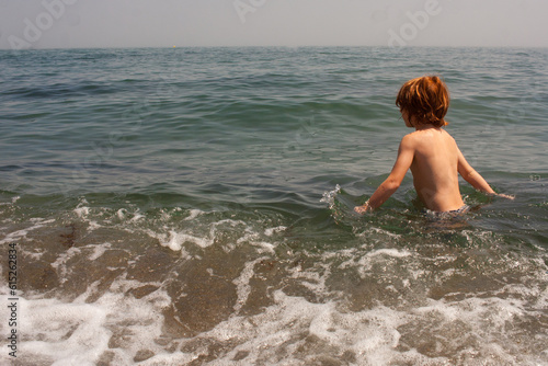 niño pelirrojo bañándose en la playa en verano © inmaleon79