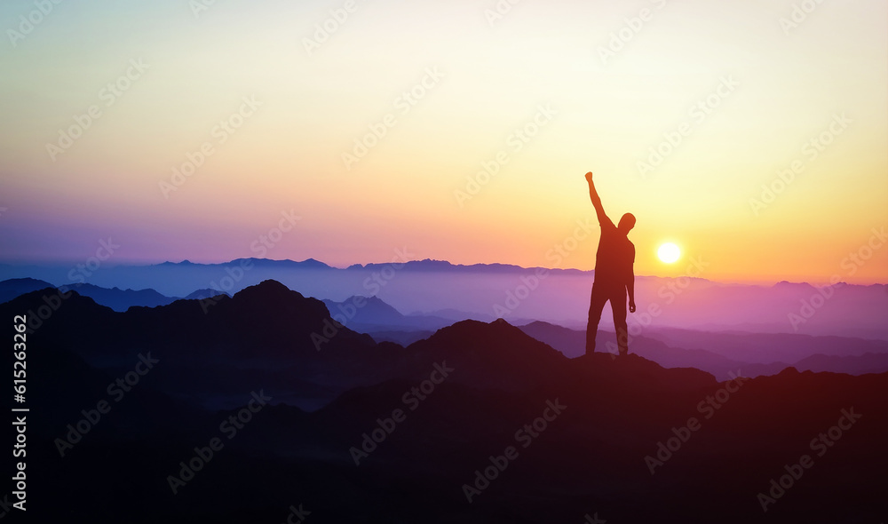 Man silhouette stand on peak of moutain with hand up. Success and motivation. Mountains landscape with sunset