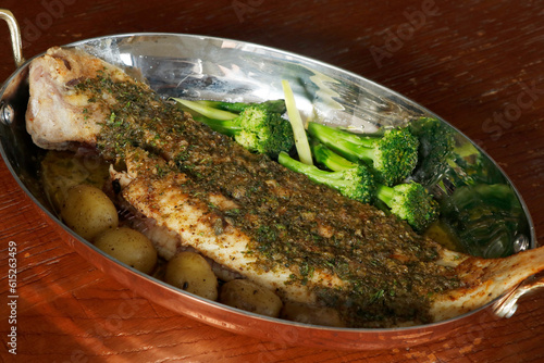 traditional french delicacy sole meuniere with green vegetables, potato and lemon capers butter in a copper pan with black background, similar to dover sole grenobloise