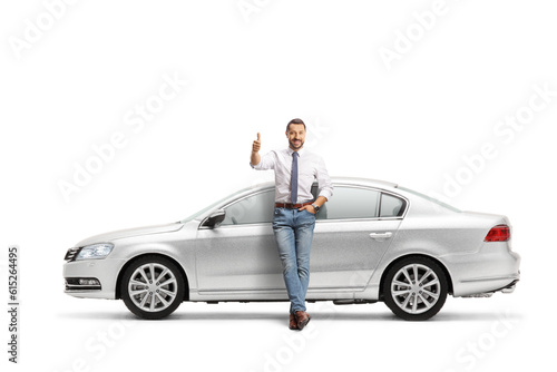 Full length portrait of a man leaning on a silver car and gesturing thumbs up