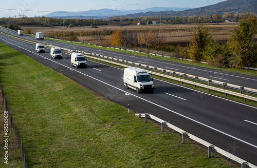 Four White delivery van on the highway. White modern delivery small shipment cargo courier van moving fast on motorway road to city urban suburb. The business distribution and logistics express servic