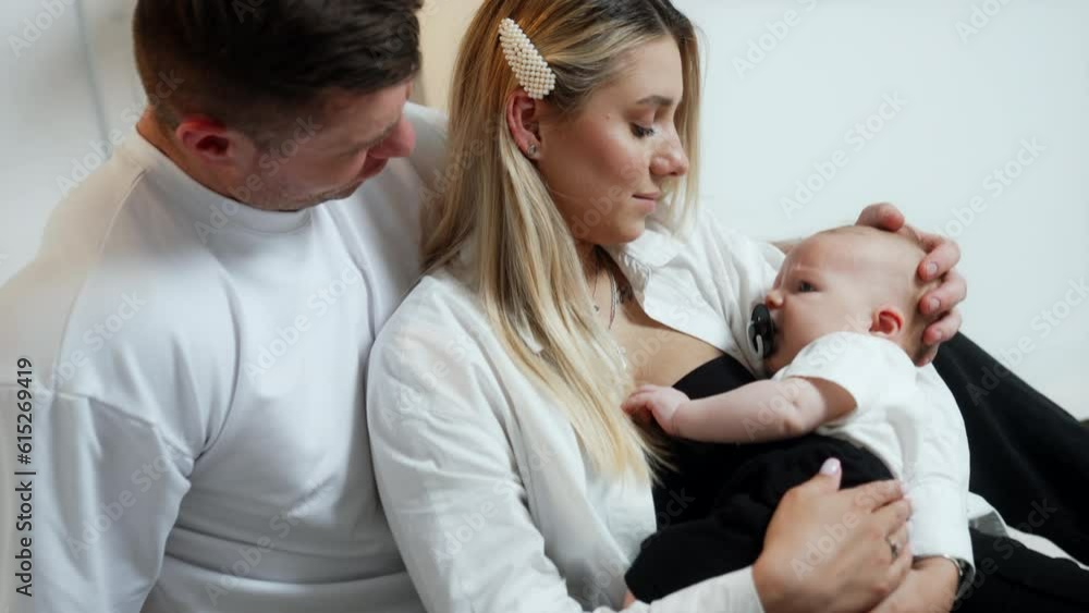 Caucasian family of three. Parents sit together looking at their newborn baby boy. Close up. Caucasian family of three. Parents sit together looking at their newborn baby boy. Close up.