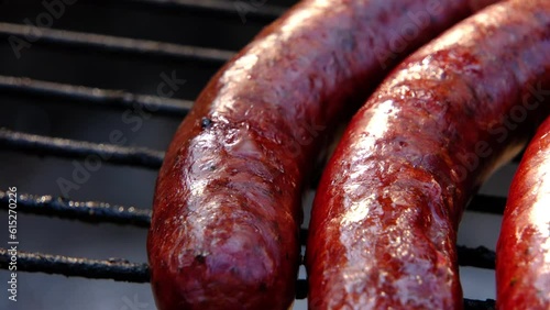 Extreme close up of smoked sausage being overcooked while grilling on the fire pit.