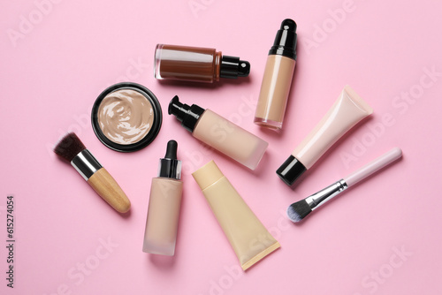 Liquid foundations and beauty accessories on pink background, flat lay