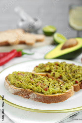 Delicious sandwiches with guacamole and ingredients on white table, closeup