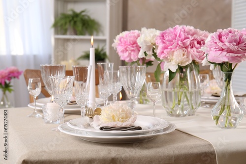 Stylish table setting with beautiful peonies and burning candles indoors