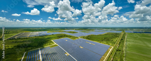 Aerial view of sustainable electric power plant between agricultural farm fields with solar photovoltaic panels for producing clean electrical energy. Renewable electricity with zero emission concept