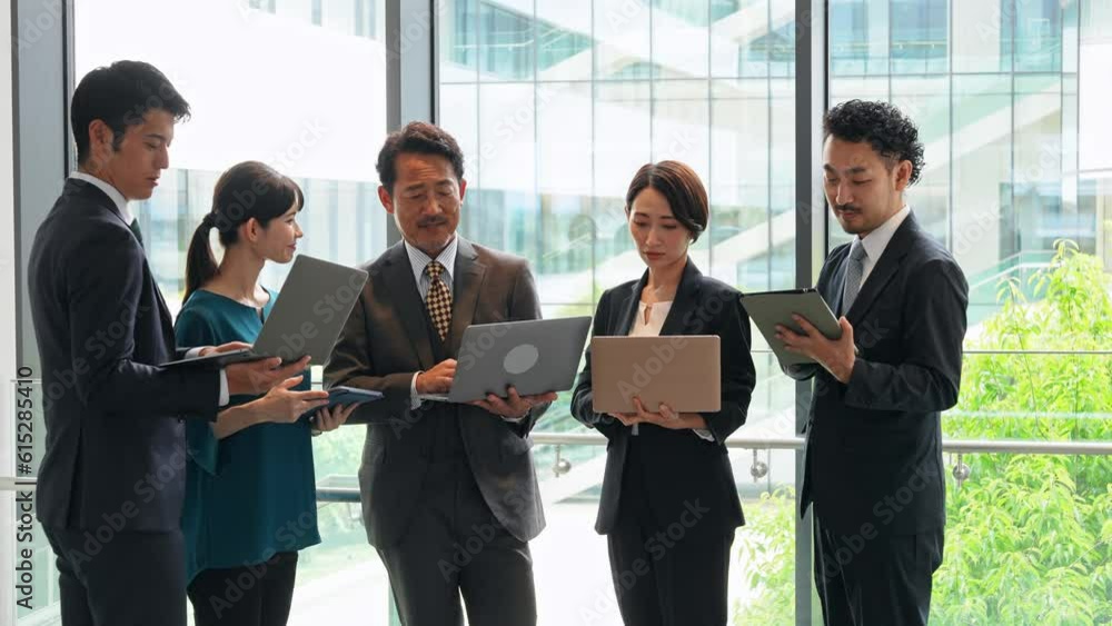 Group of Asian businesspeople meeting in lobby with laptops and tablets. Digital transformation. Smart office. Group of Asian businesspeople meeting in lobby with laptops and tablets. Digital transformation. Smart office.