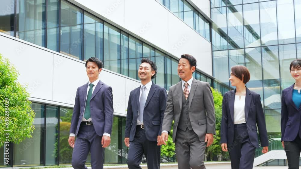 A group of business people of various generations walking in front of an office building with smiles. A group of business people of various generations walking in front of an office building with smiles.