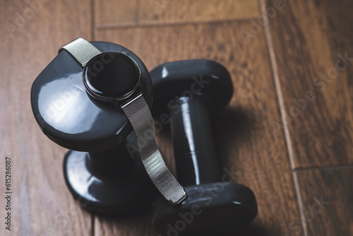 Connected Fitness: Smartwatch and Dumbbells on Wooden Floor.