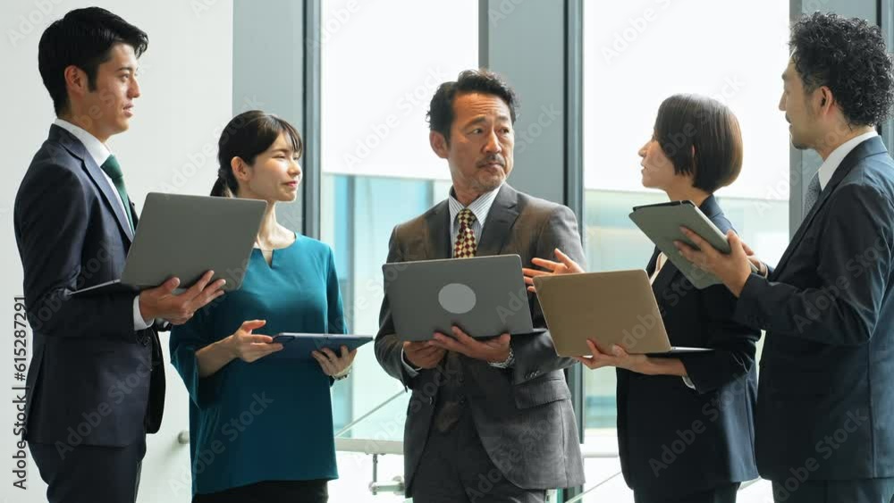Group of Asian businesspeople meeting in lobby with laptops and tablets. Digital transformation. Smart office. Group of Asian businesspeople meeting in lobby with laptops and tablets. Digital transformation. Smart office.
