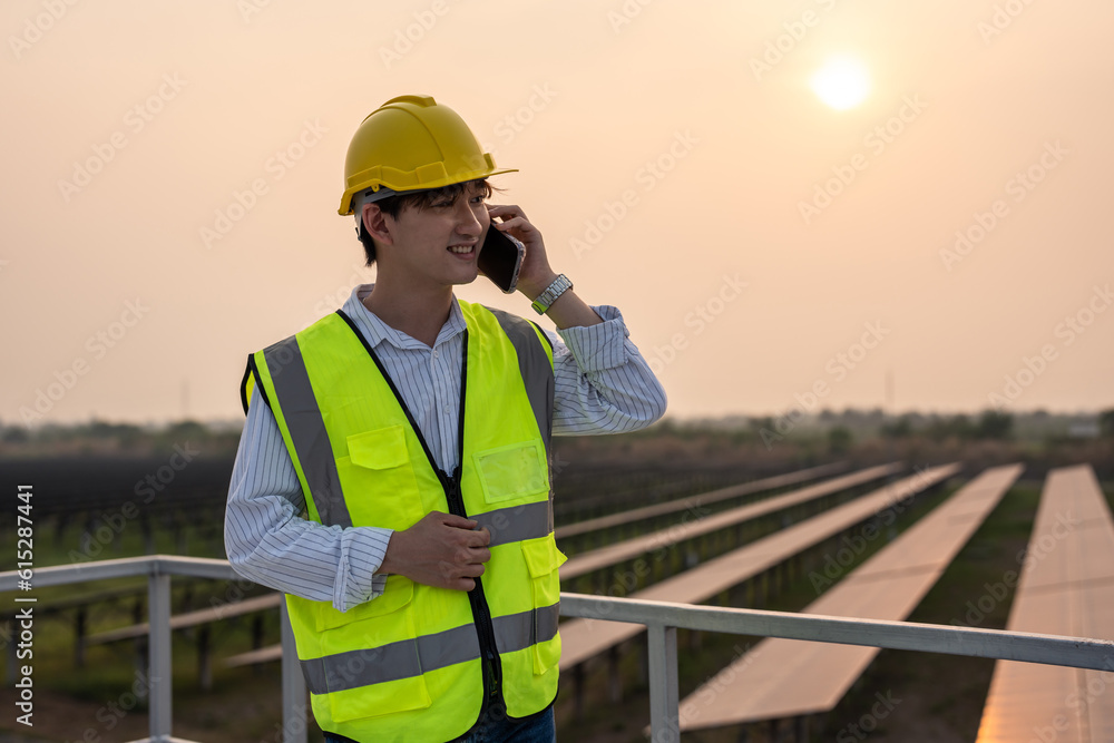 Asian young engineer talking on phone while work at solar cell field. Asian young engineer talking on phone while work at solar cell field.
