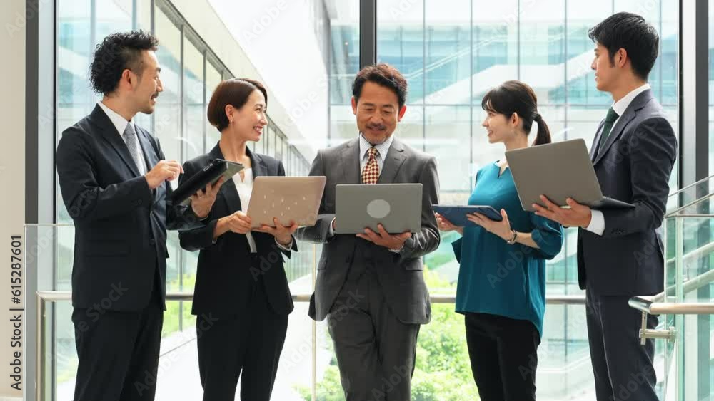 Group of Asian businesspeople meeting in lobby with laptops and tablets. Digital transformation. Smart office. Group of Asian businesspeople meeting in lobby with laptops and tablets. Digital transformation. Smart office.