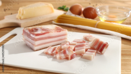 Sliced pancetta, smoked bacon on a cutting board. Ingredient for pasta carbonara. Cooking traditional Italian food.