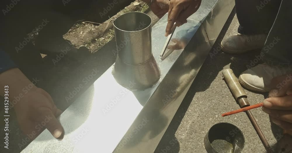 Zinc rain gutter welding by using soldering copper. Technician is