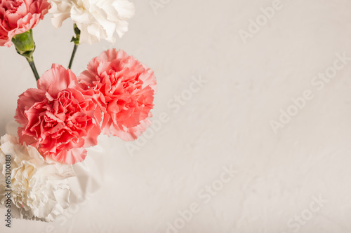 Pink carnations in a white vase on a white table. Top view. Place for text.